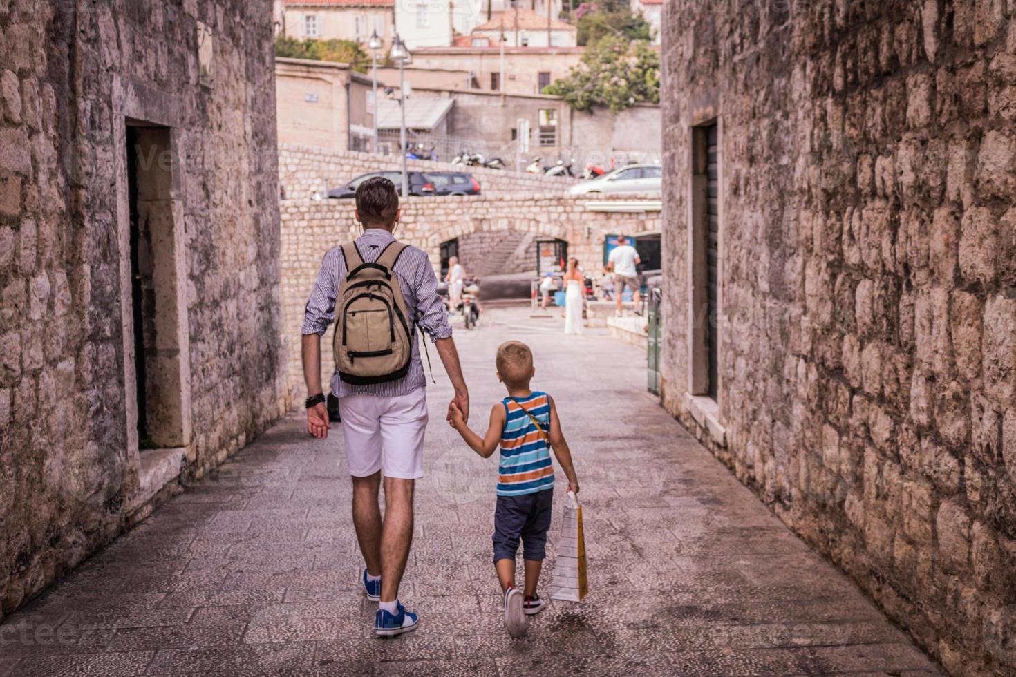vader en zoon lopen door de stad en houden elkaars hand vast foto