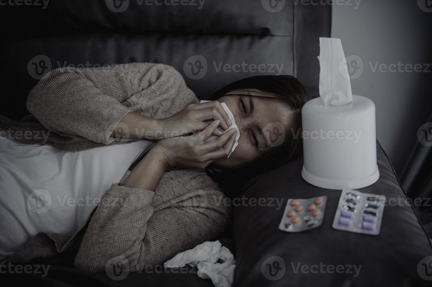 Aziatische zieke vrouw zit op de bank, blijf thuis, de vrouw voelde zich slecht, wilde gaan liggen en rusten, hoge koorts foto