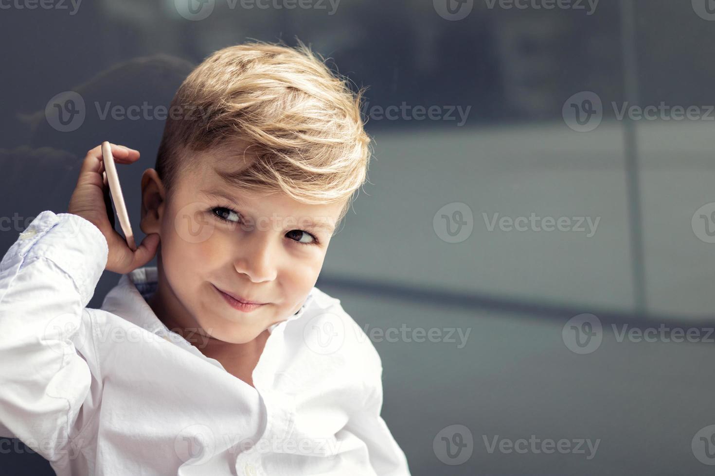 schattige kleine jongen praten over de mobiele telefoon foto