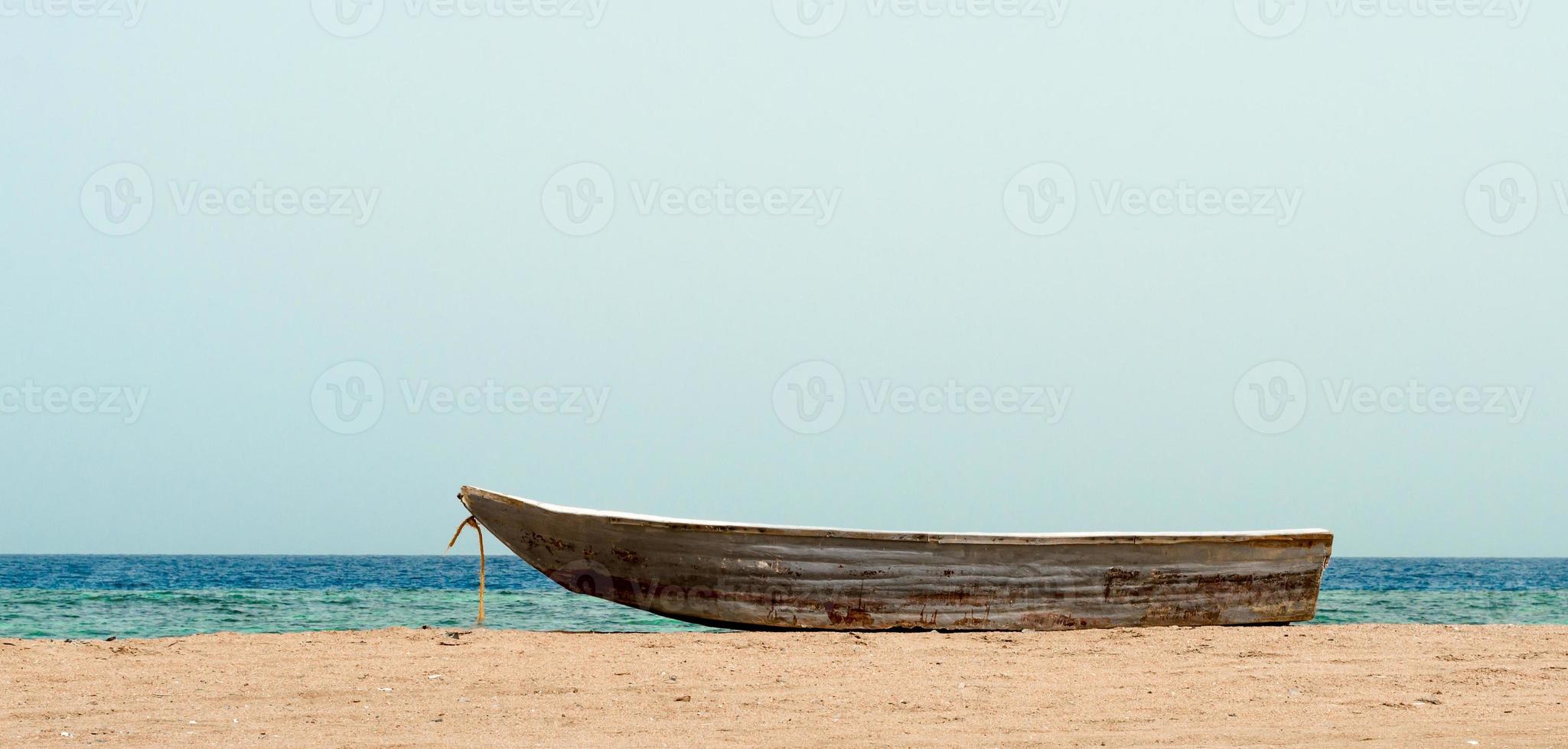 oude boot op het zand tegen de zee foto