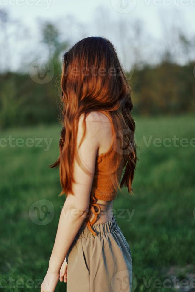 een vrouw in natuur in een groen park staat met haar terug naar de camera en horloges de zonsondergang buitenshuis foto