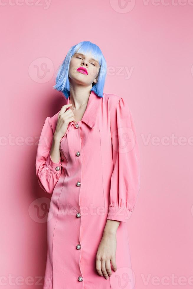 portret van een vrouw in blauw pruik roze jurk rood lippen roze achtergrond foto