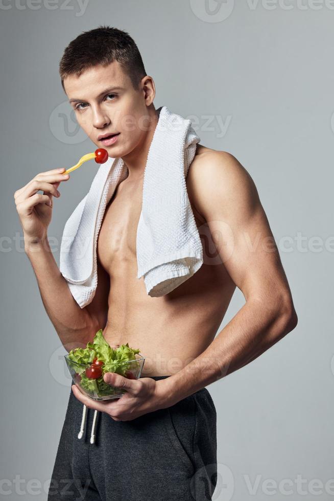 sportief Mens Aan aan het eten vers salade handdoek Aan schouders geïsoleerd achtergrond foto