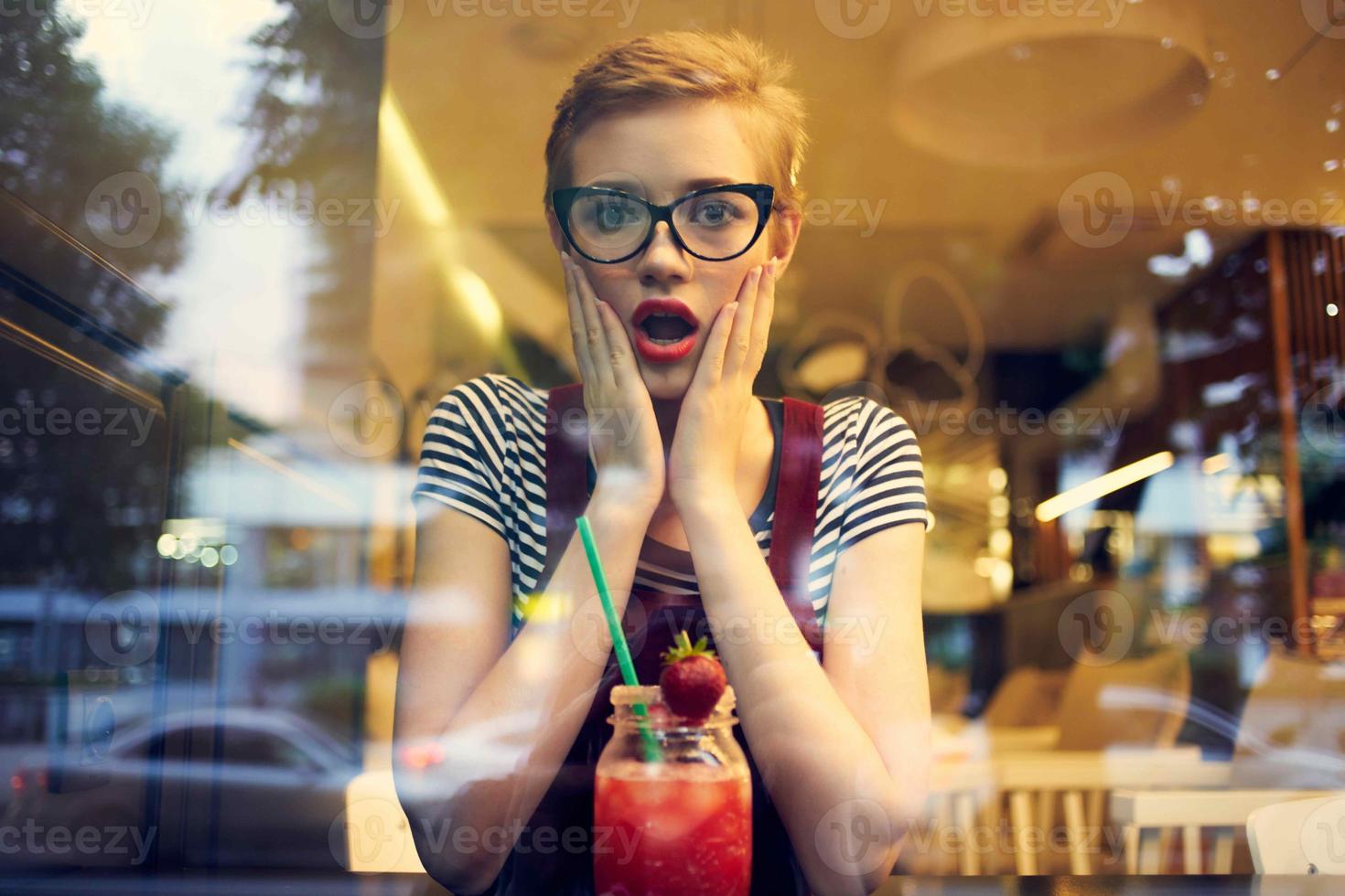 vrouw in bril met kort haar- zit in een cafe eenzaamheid cocktail rust uit foto