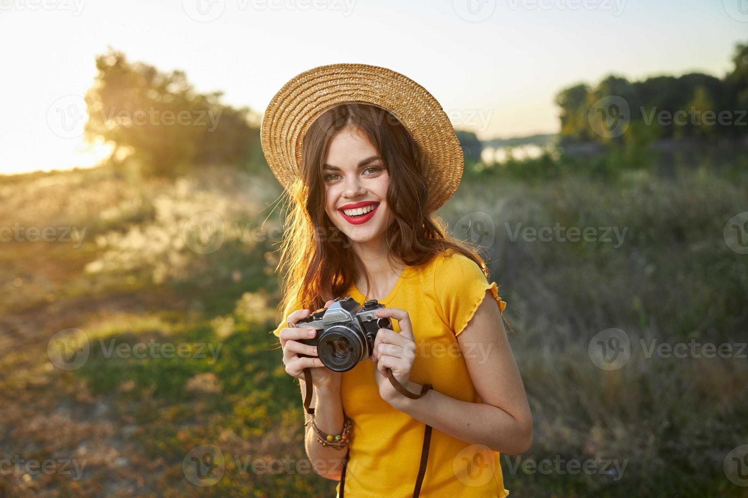 vrouw fotograaf camera in handen glimlach rood lippen hoed aantrekkelijk kijken natuur foto