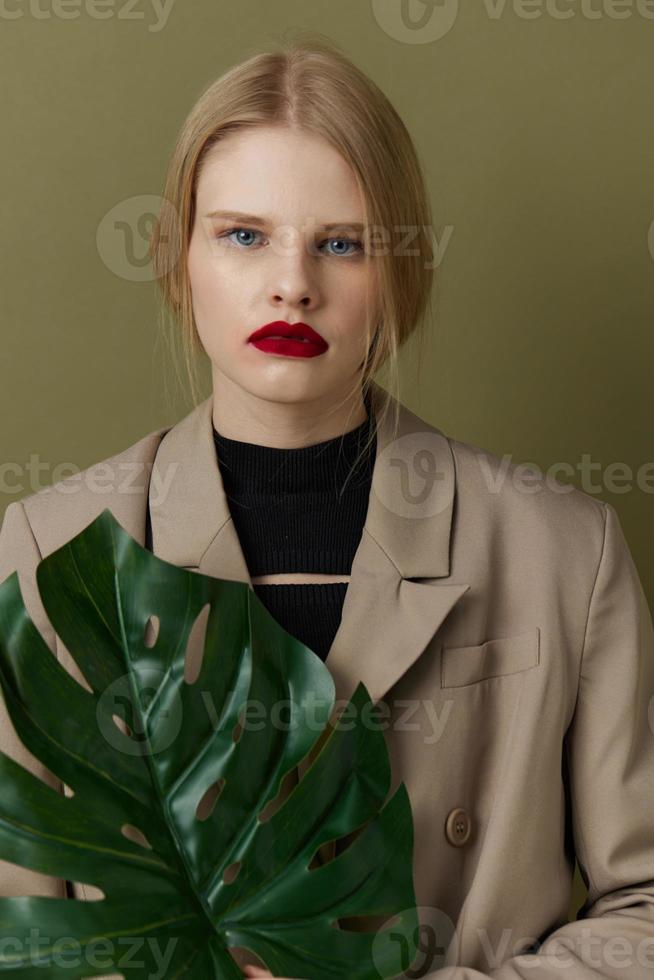 portret van een vrouw in jas rood lippen mode palm blad levensstijl poseren foto