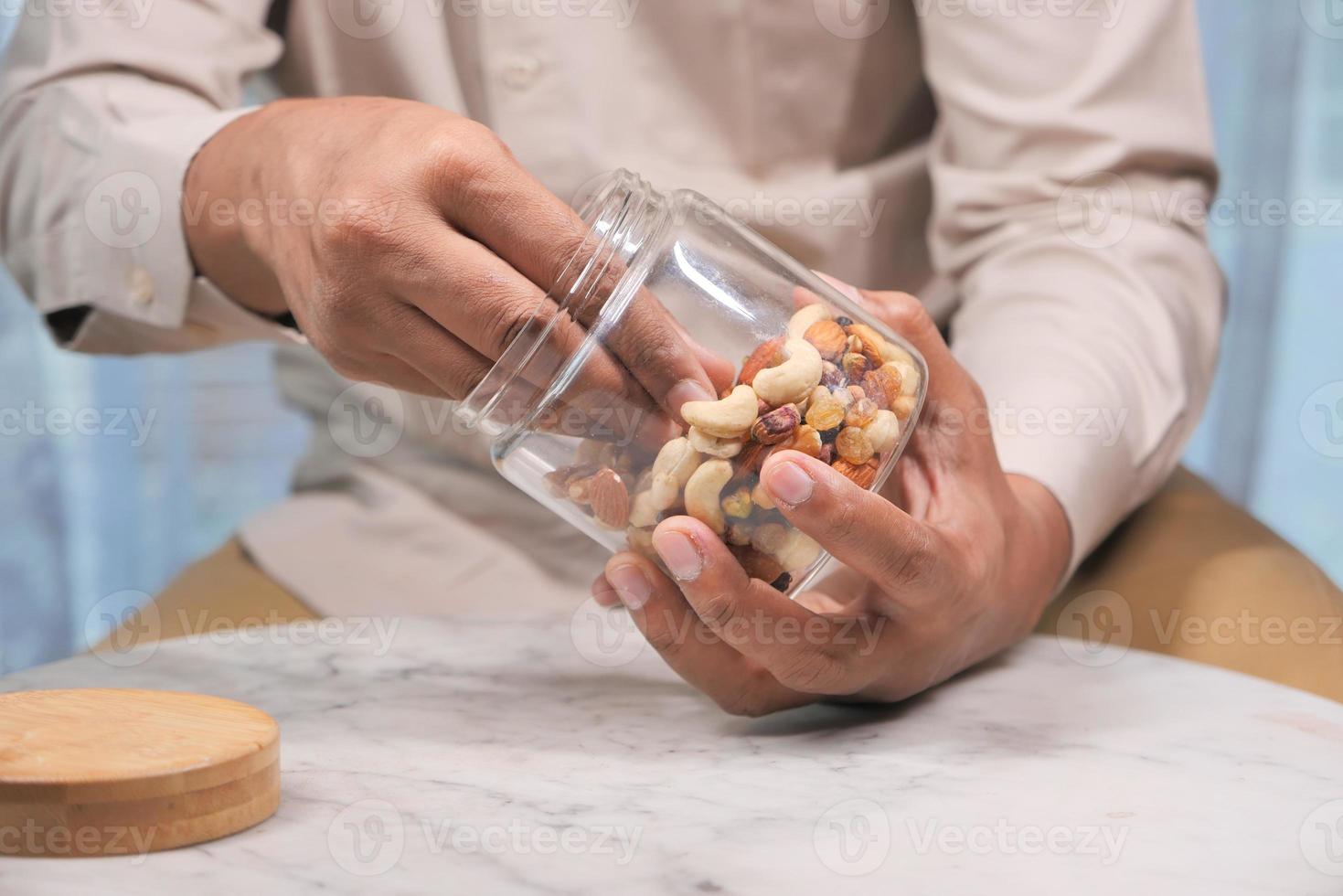 man eet gemengde noten uit een pot foto