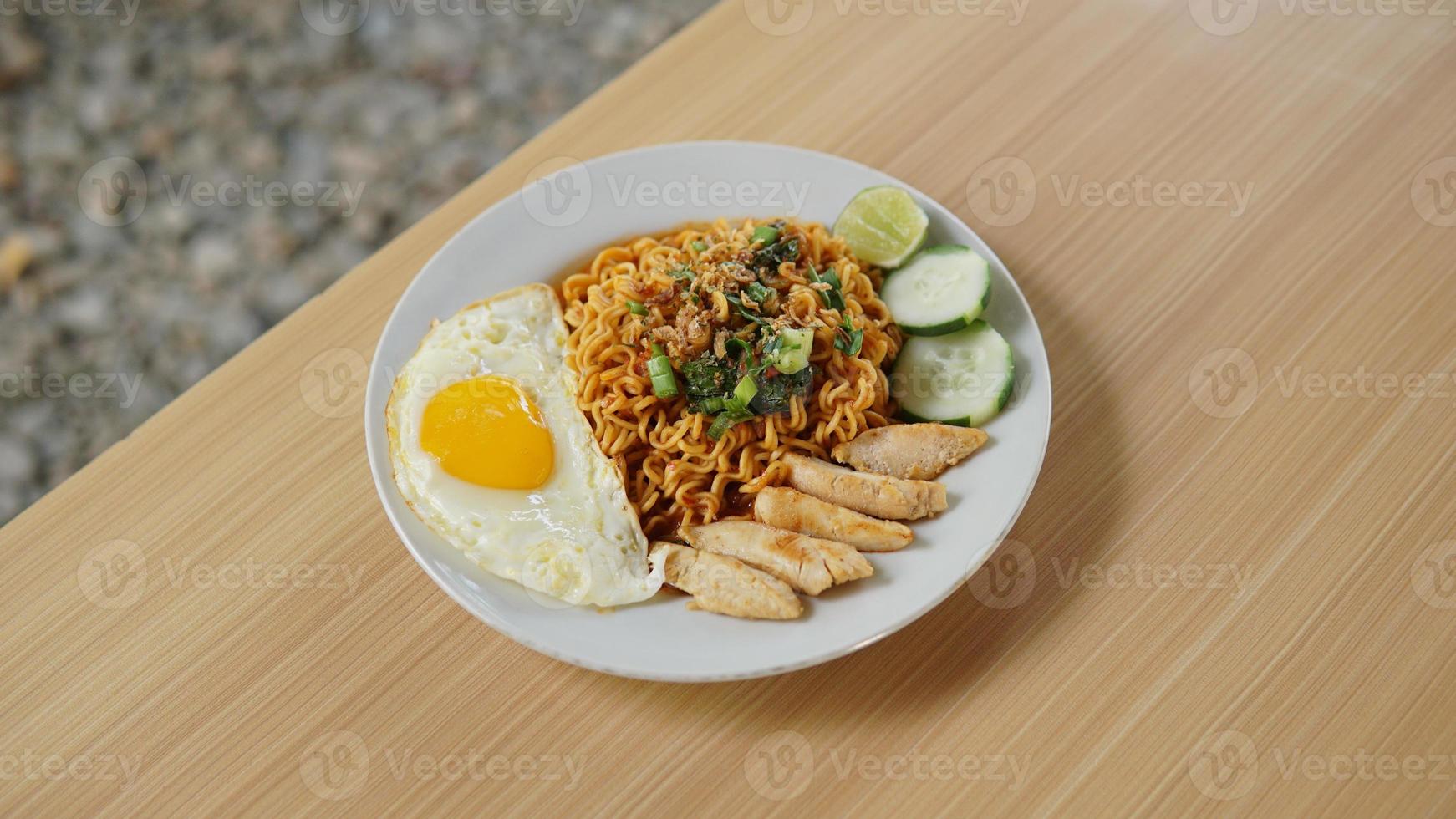 gebakken ogenblik noodle met kip kotelet en gebakken ei Aan houten tafel foto