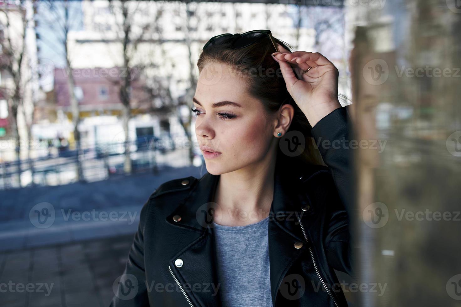 vrouw in leer jasje Aan de straat in de stad en editie zonnebril in de achtergrond foto