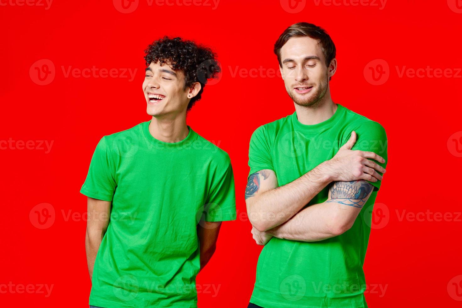 blij vrienden in groen t-shirts zijn staand De volgende naar rood achtergrond foto