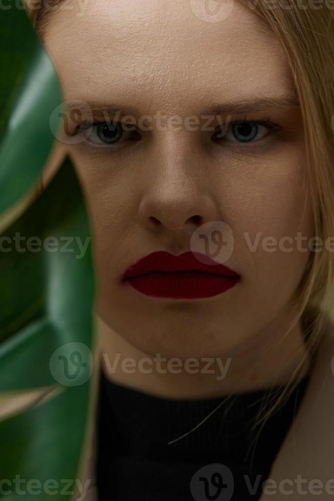 vrouw met rood lippen groen bladeren dichtbij omhoog foto