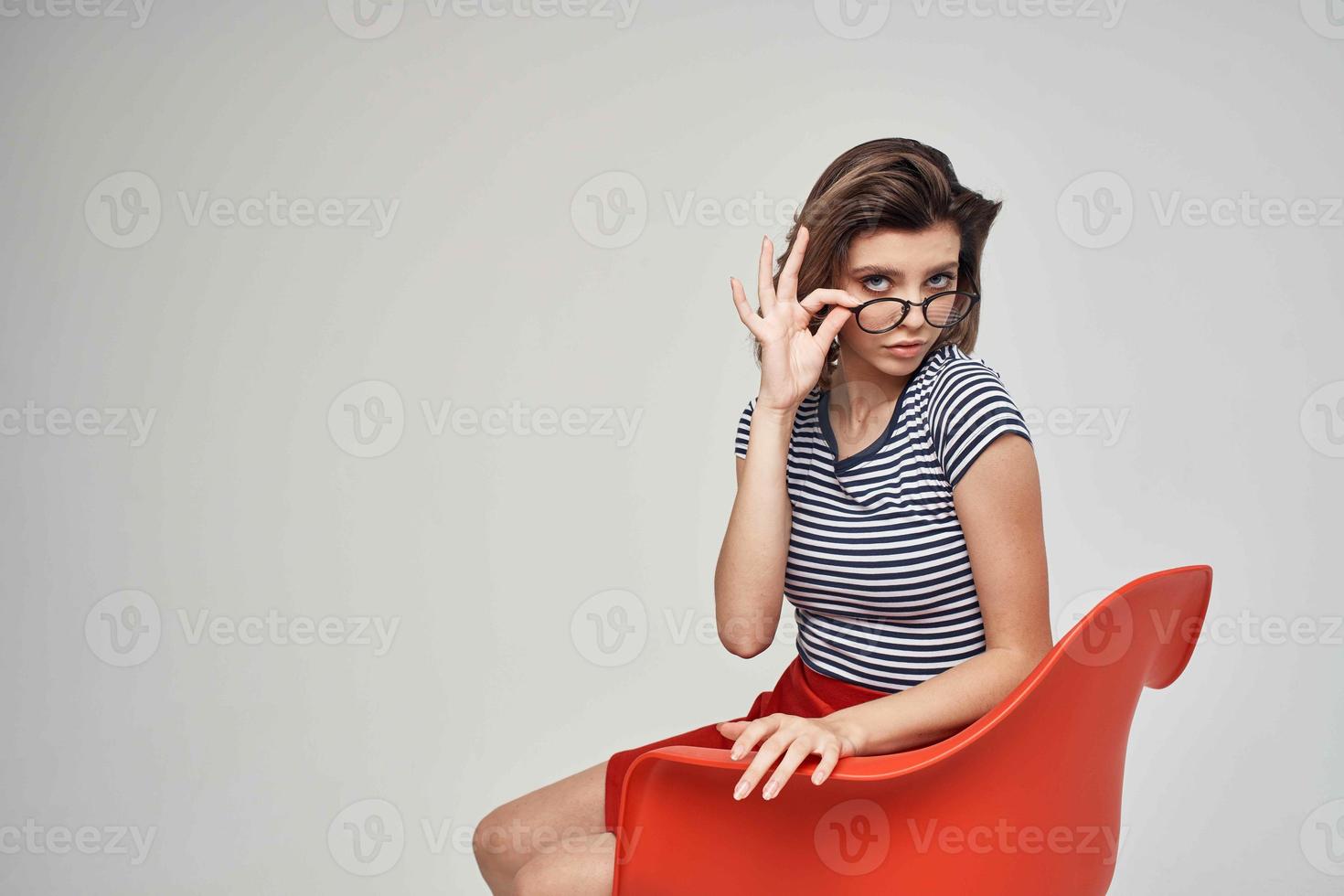vrouw in een gestreept t-shirt zittend Aan de rood stoel modern stijl kapsel foto