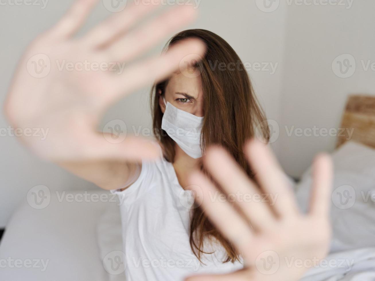 vrouw in medisch masker gebaren met haar handen in een licht kamer bijgesneden visie foto