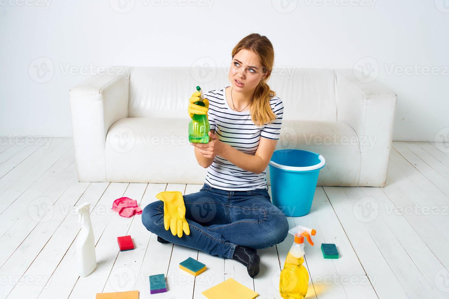 vrouw zittend Aan de verdieping met schoonmaak benodigdheden schoonmaak onderhoud huiswerk foto