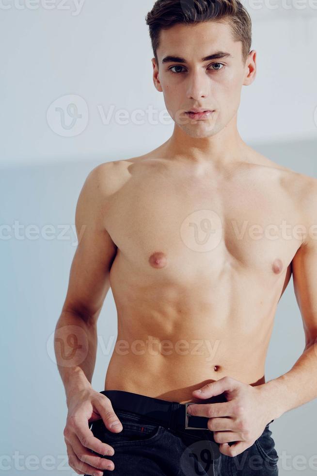 knap jong Mens met een naakt torso Aan een grijs achtergrond en bijgesneden visie foto