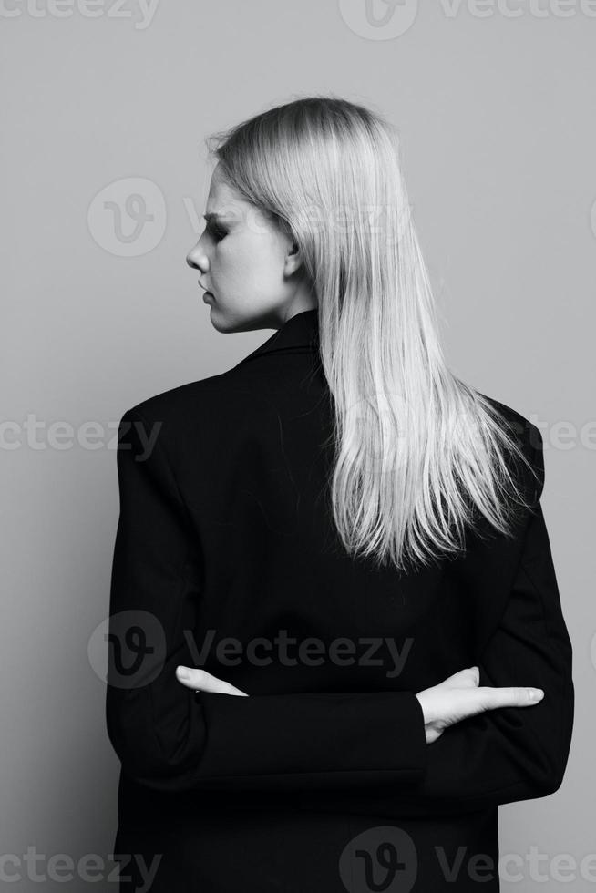 de concept van kunst fotografie. een elegant meisje kruisen haar armen achter haar terug bochten haar hoofd en poses met haar terug in een zwart jasje in de studio. mode banier foto