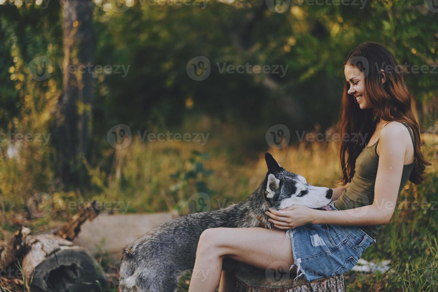 vrouw en haar schor hond gelukkig spelen buitenshuis in de park tussen de bomen glimlach met tanden in de herfst wandelen met haar huisdier foto