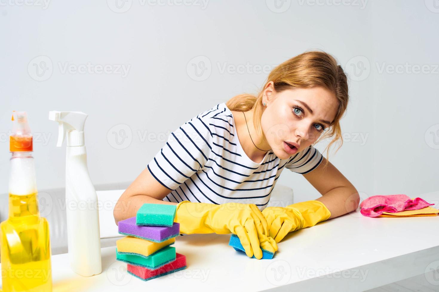 vrolijk schoonmaak dame doekjes de tafel met wasmiddelen schoonmaak gereedschap foto