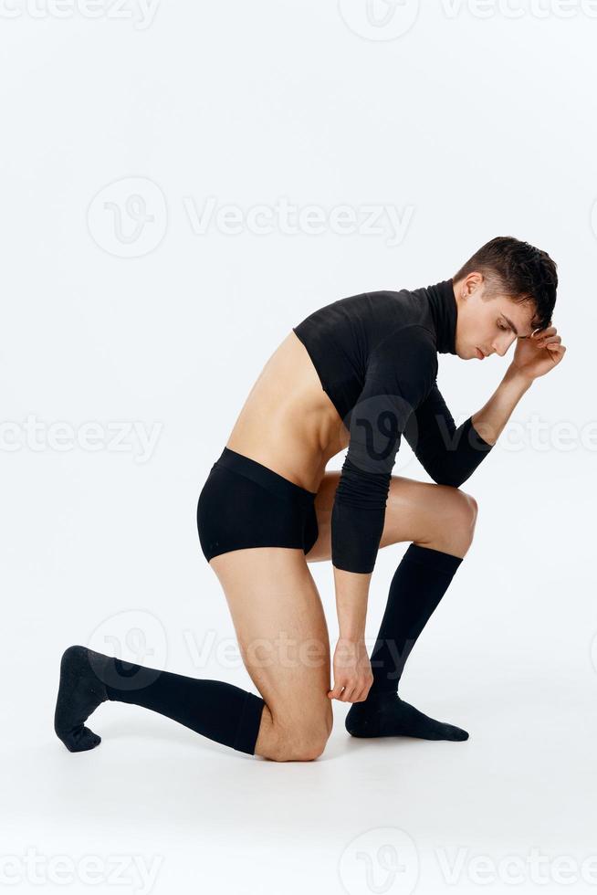 een Mens in een trui en sokken en onderbroek knielt in vol groei Aan een licht achtergrond foto
