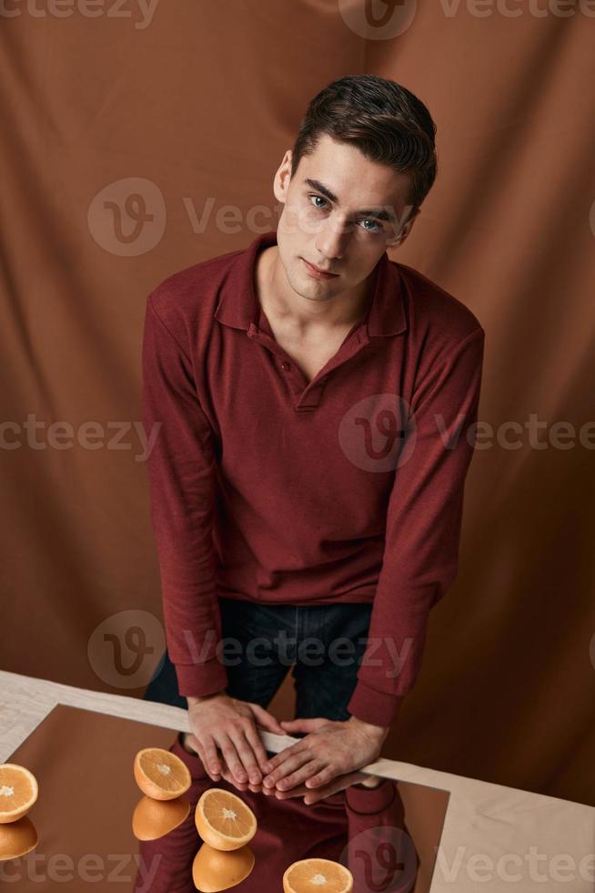 mooi hoor Mens in een rood overhemd met sinaasappels Aan de studio spiegel foto