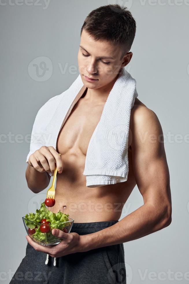 sportief Mens met handdoek Aan schouders bord van salade gezond tussendoortje training foto