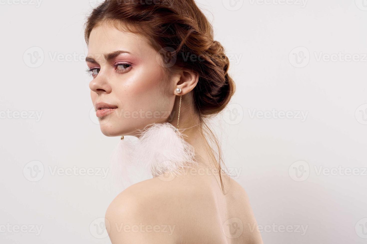 vrouw met kaal schouders pluizig oorbellen mode dichtbij omhoog foto