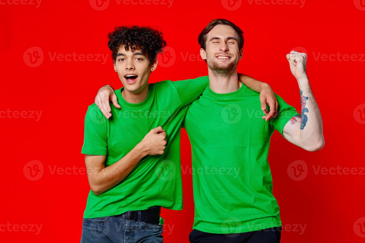 twee vrolijk vrienden knuffel groen t-shirts emoties communicatie rood achtergrond foto