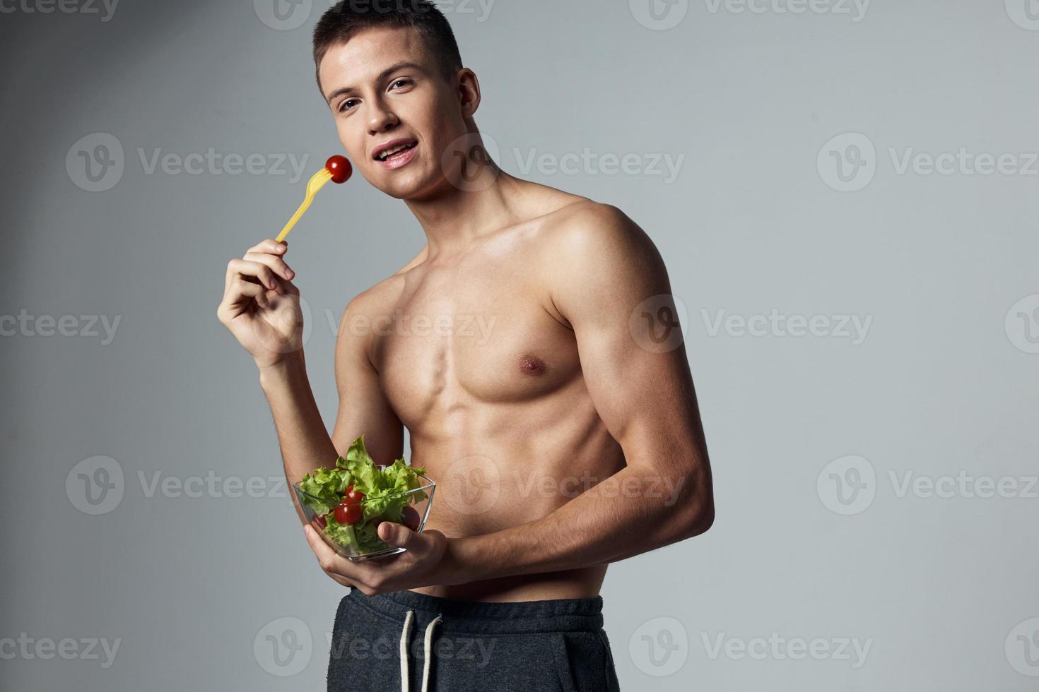 atletisch Mens met gemotiveerd omhoog buikspieren gezond voedsel sla blad training foto