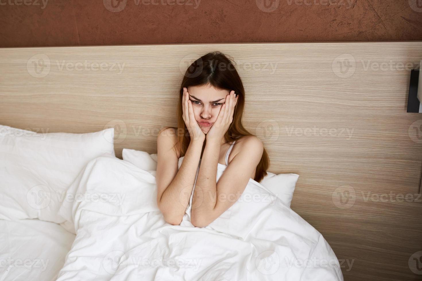 vrouw werd wakker omhoog vroeg in de ochtend- en tintje haar gezicht met haar handen onder de covers in bed foto