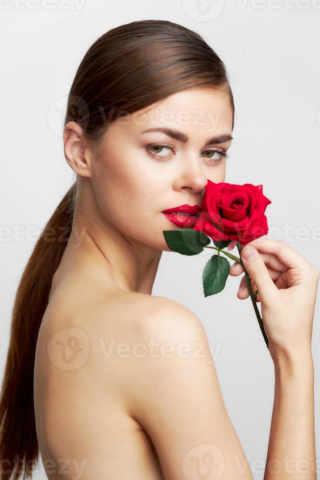 vrouw met lang met een roos in de buurt de gezicht voor kapsel lippenstift foto