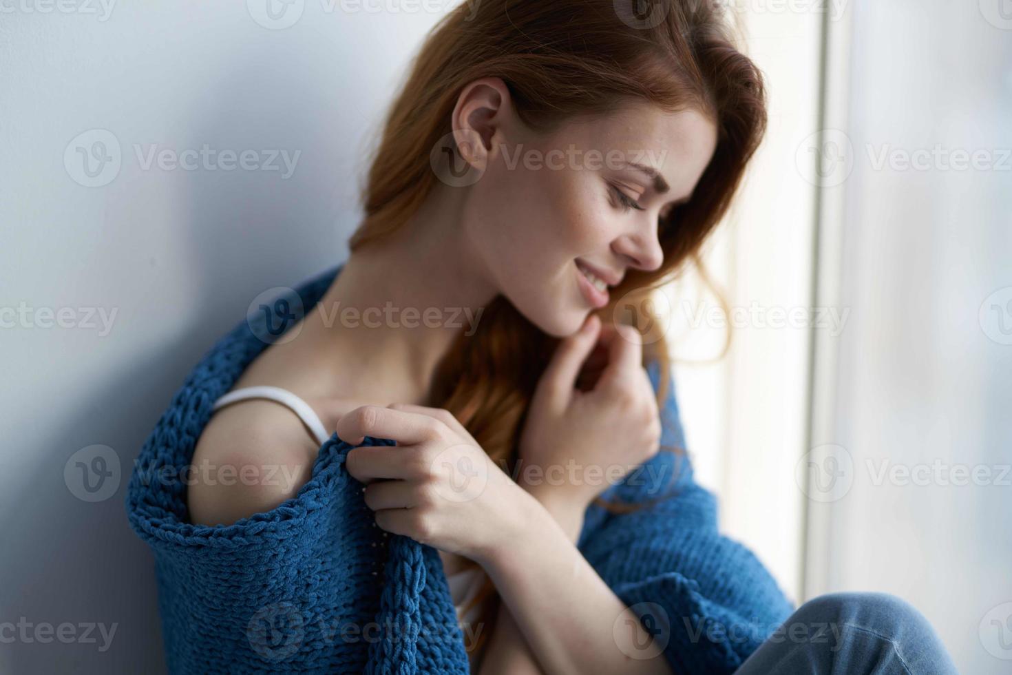 vrouw zittend in de buurt de venster met een blauw plaid glimlach Bij huis foto