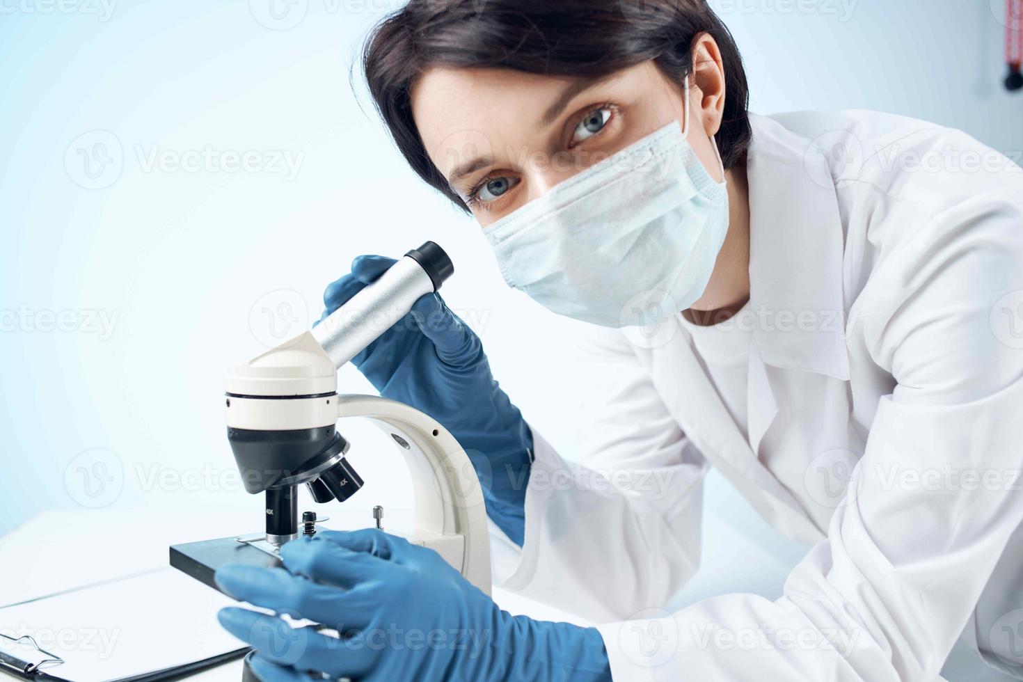 laboratorium assistent vervelend een medisch masker op zoek door een microscoop professioneel Onderzoek experiment foto