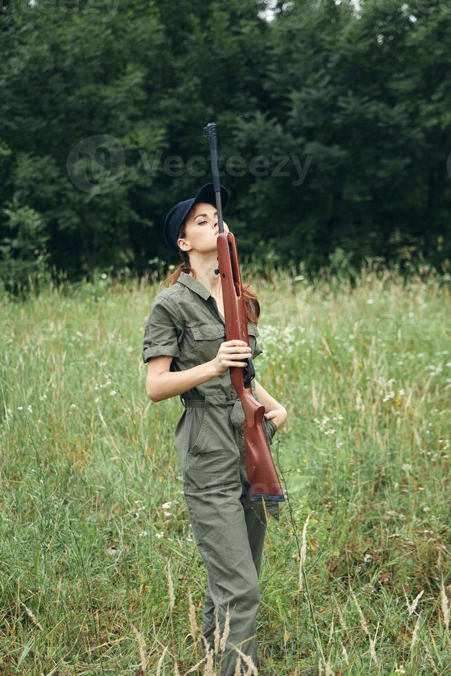 vrouw soldaat Holding een geweer in voorkant van hem groen jumpsuit reizen levensstijl vers lucht foto