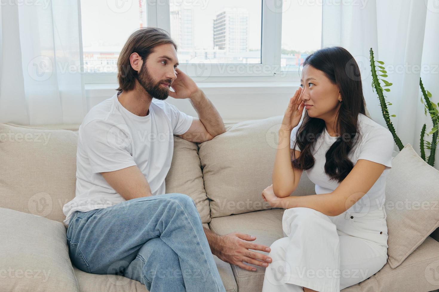 een Mens en een vrouw van verschillend races zitten Aan de bankstel in een kamer Bij huis en praten over hun problemen naar elk ander. een stress-vrij levensstijl van familie ruzies met psychologisch ondersteuning foto