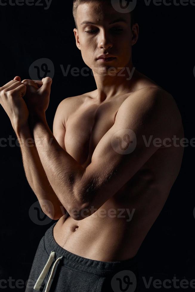 sportief vent Aan zwart achtergrond houdt handen in de buurt gezicht voor bijgesneden visie van biceps spieren foto