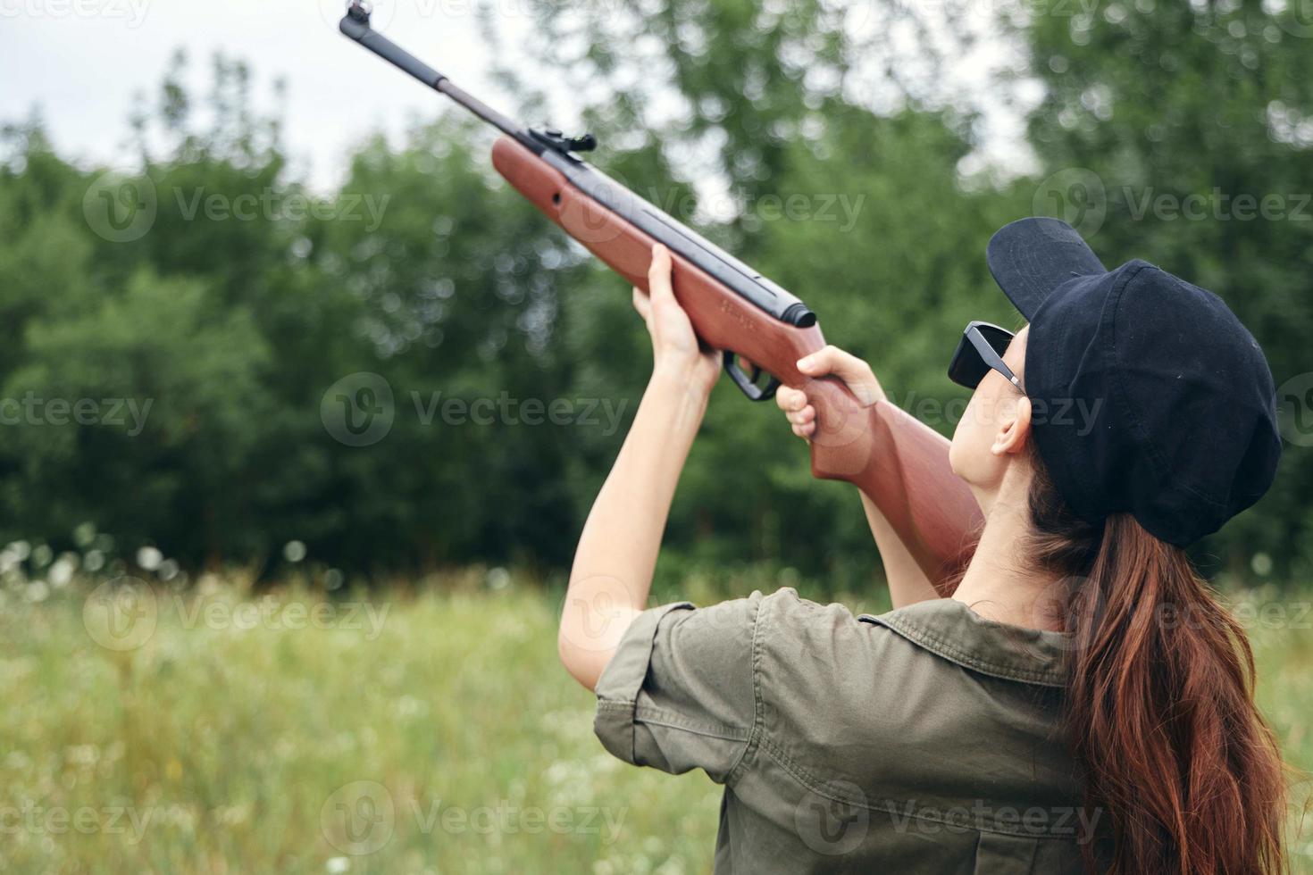 vrouw Aan natuur Holding een geweer omhoog jacht- terug visie zwart pet foto