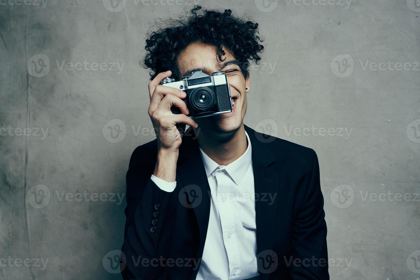 krullend haar Mens in een klassiek pak looks Bij de camera in zijn hand- studio hobby foto