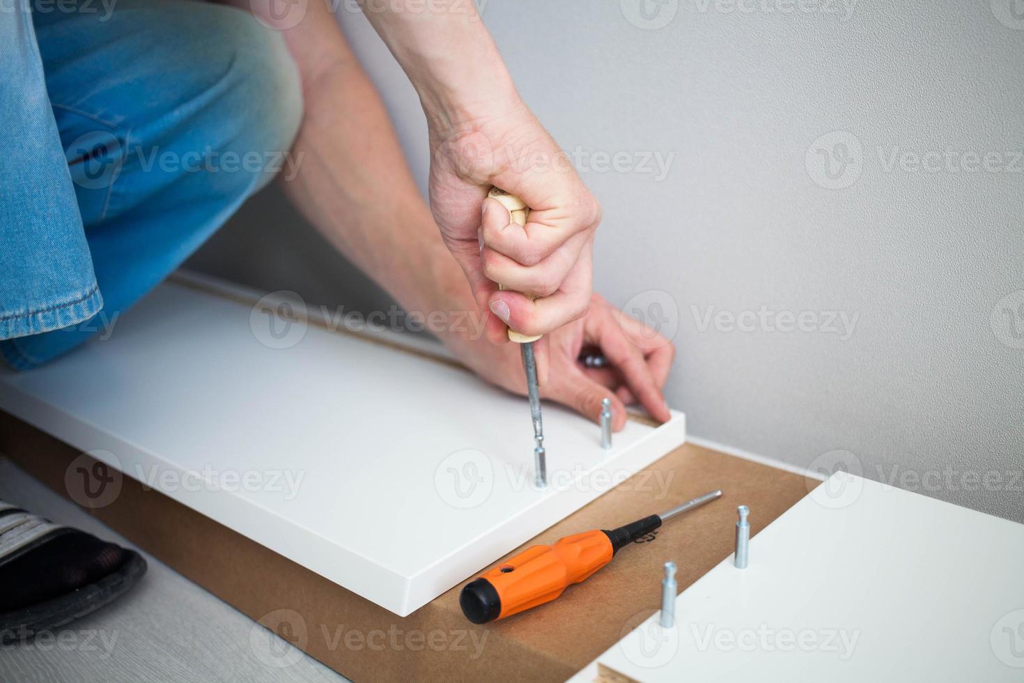 dichtbij omhoog van Mens hand, meubilair assembler maken vlak pak wit meubilair bijeenkomst onderhoud Bij huis. foto