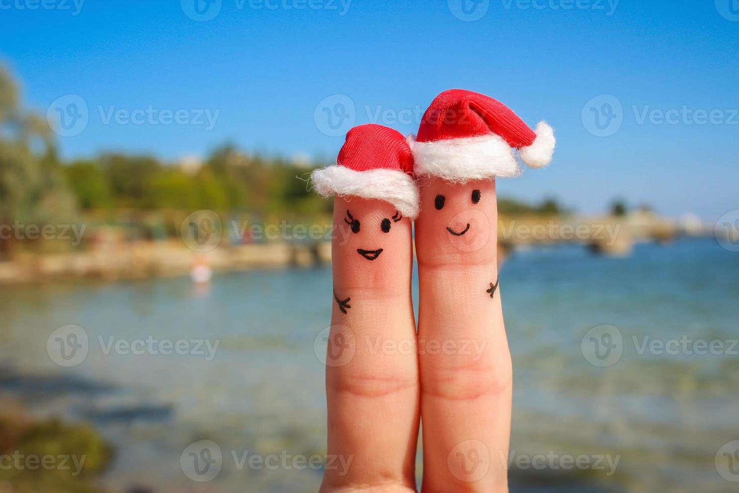 vinger kunst van gelukkig paar in Kerstmis hoeden resting Aan de zee foto