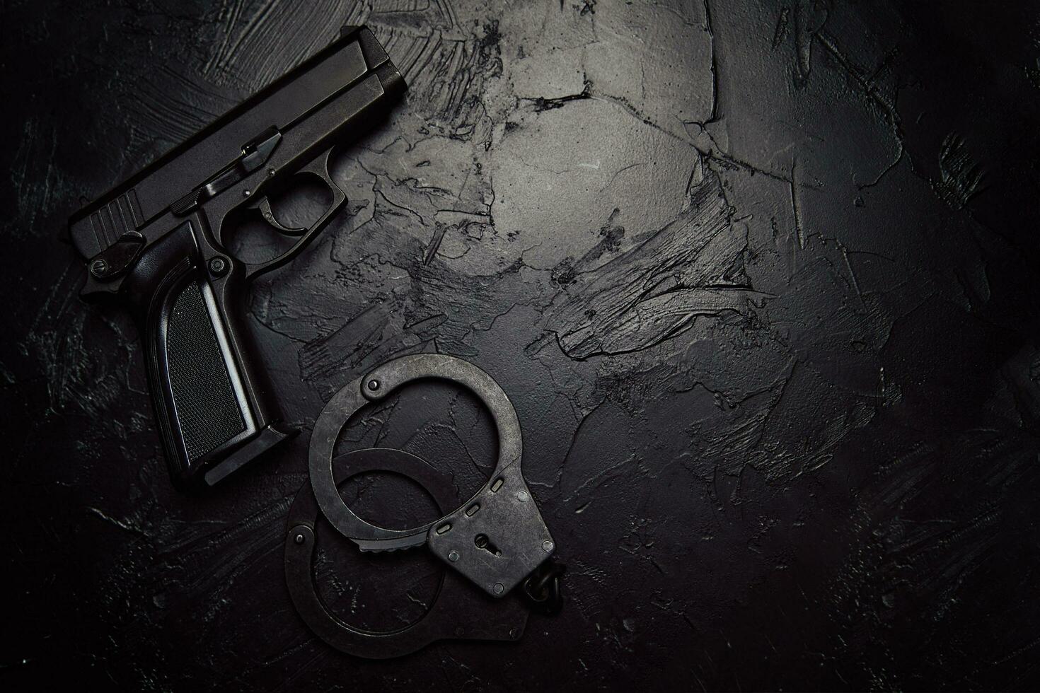 pistool en handboeien op zwarte getextureerde tafel foto