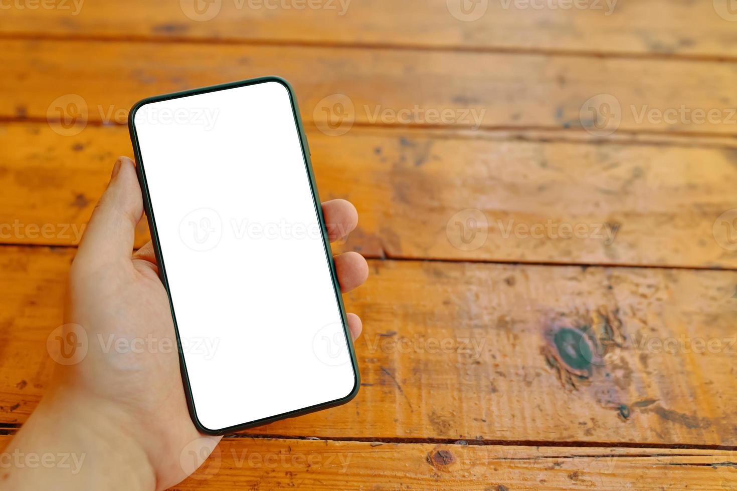man's hand houdt smartphone over houten tafel foto