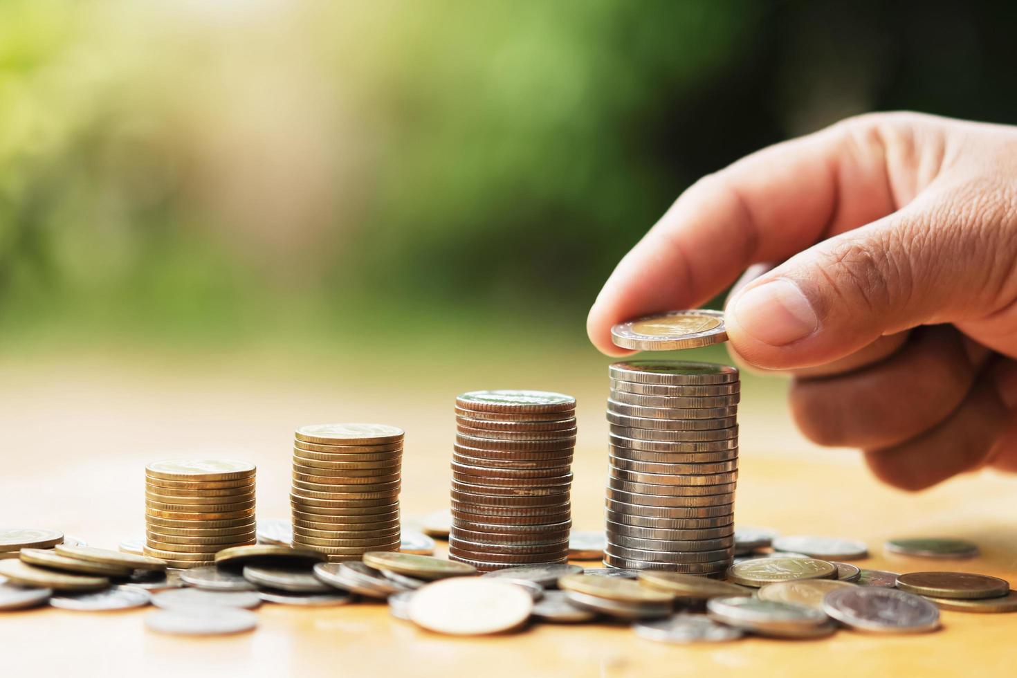 besparing geld hand- zetten munten Aan stack Aan tafel met zonneschijn. concept financiën en accounting foto