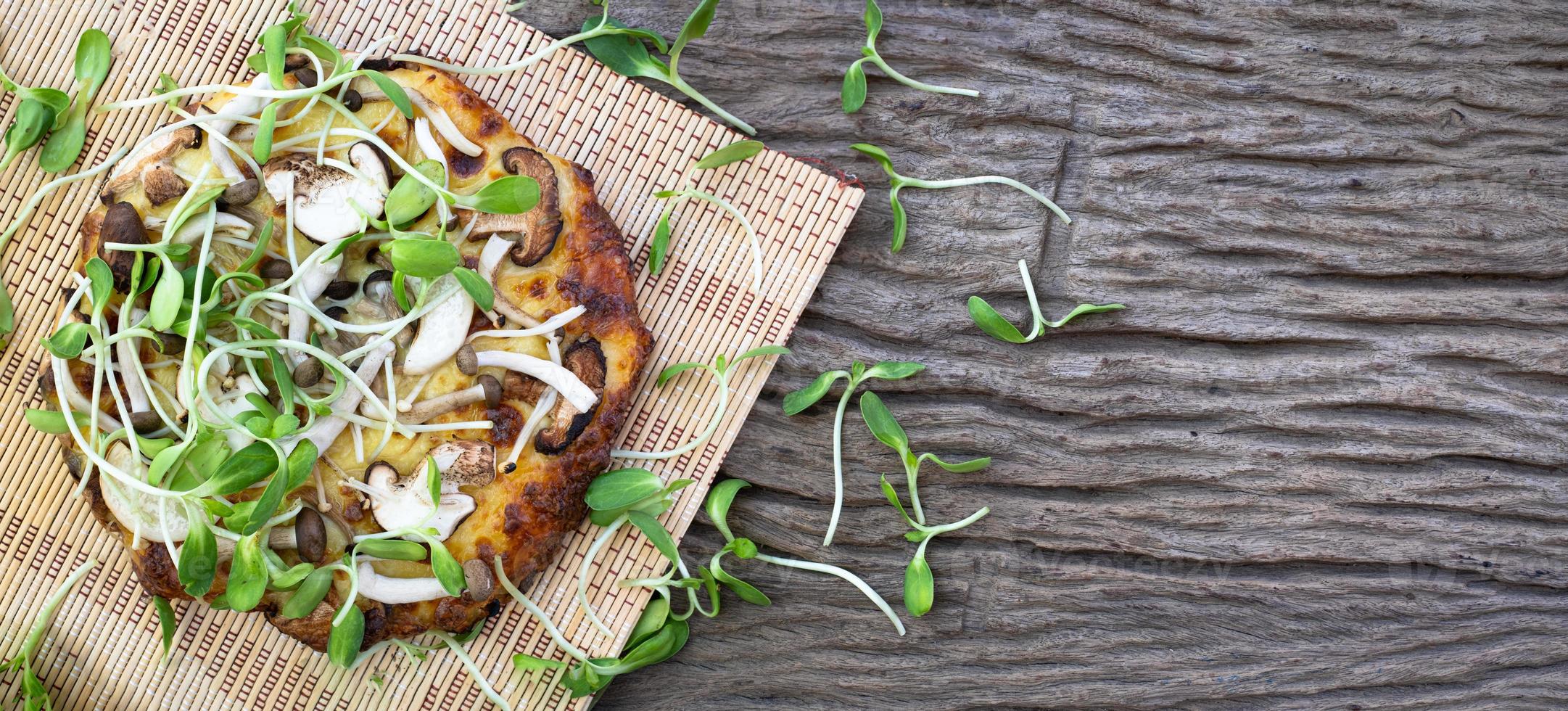 zelfgemaakte vegetarische pizza met zonnebloem spruiten op een houten tafel achtergrond foto