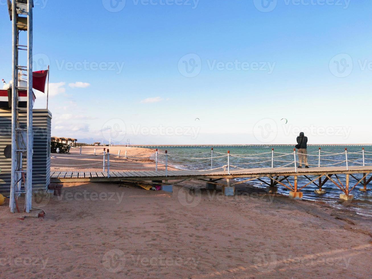 Mens staat Aan de pier en duurt afbeeldingen van paragliden foto