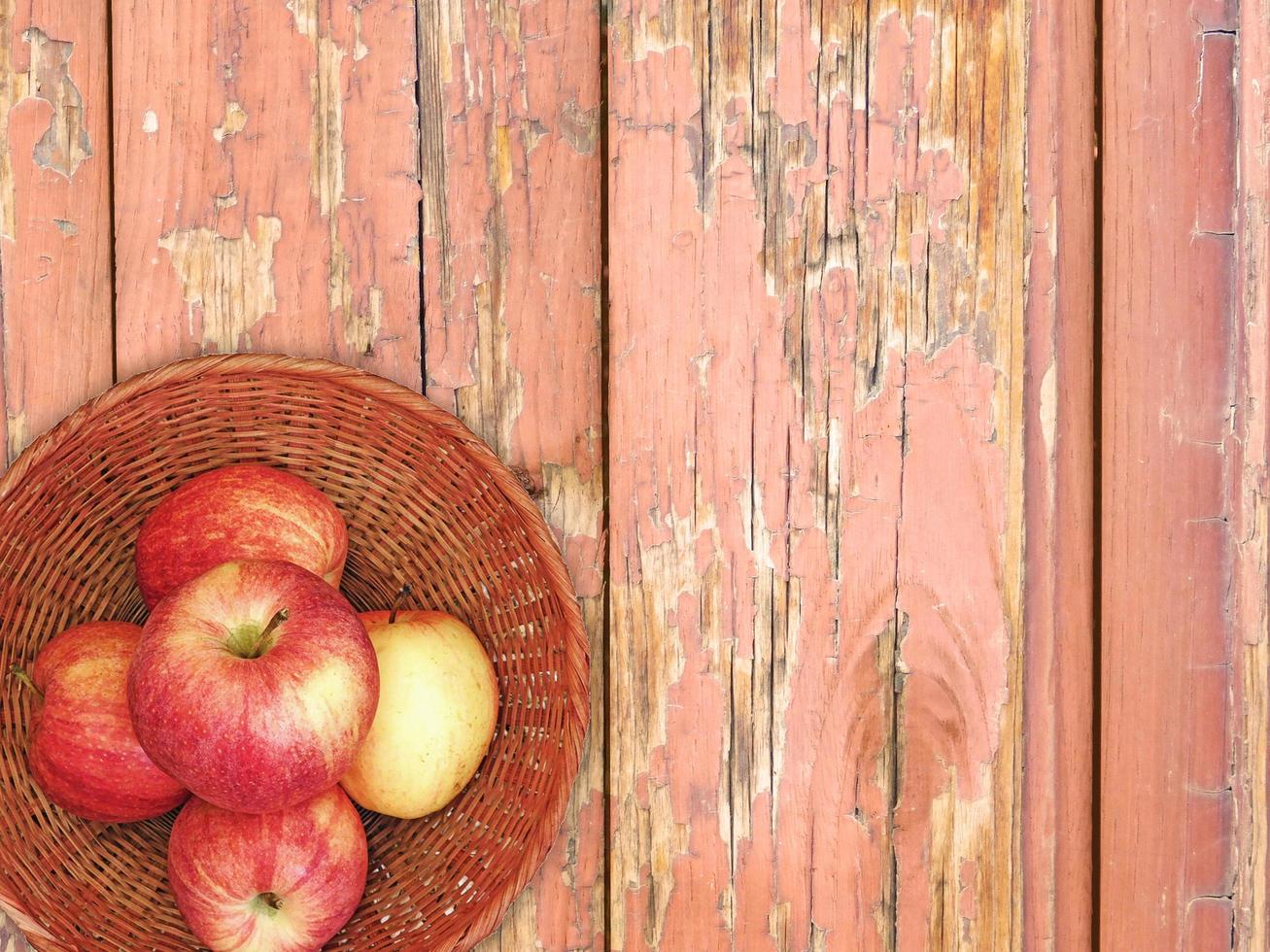 rode appels op een rieten plaat op een houten tafel achtergrond foto