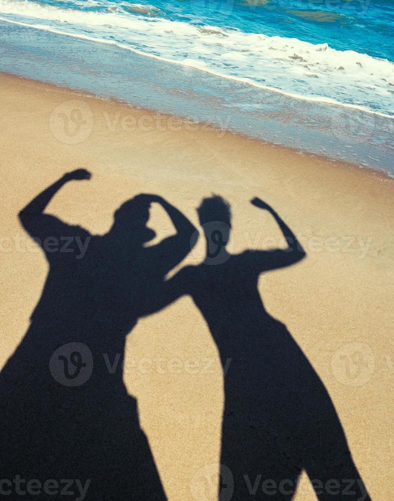 silhouetten van twee mensen op een strand foto