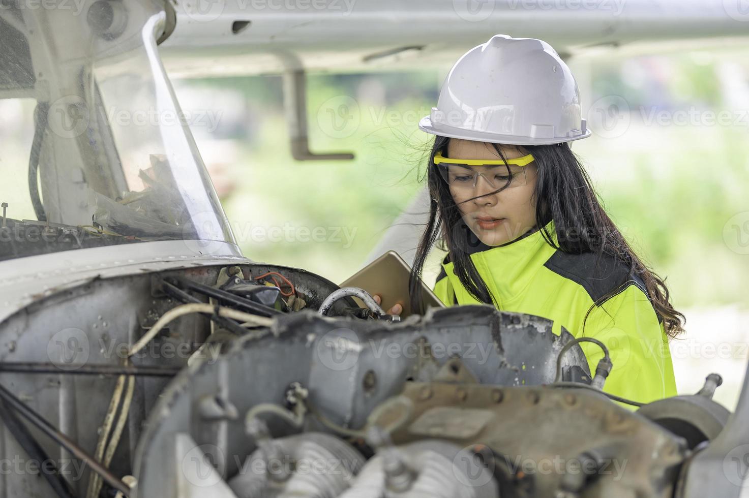 technicus die de motor van het vliegtuig repareert, vrouwelijke lucht- en ruimtevaarttechniek die vliegtuigmotoren controleert, aziatisch monteur onderhoud inspecteert vliegtuigmotor; foto