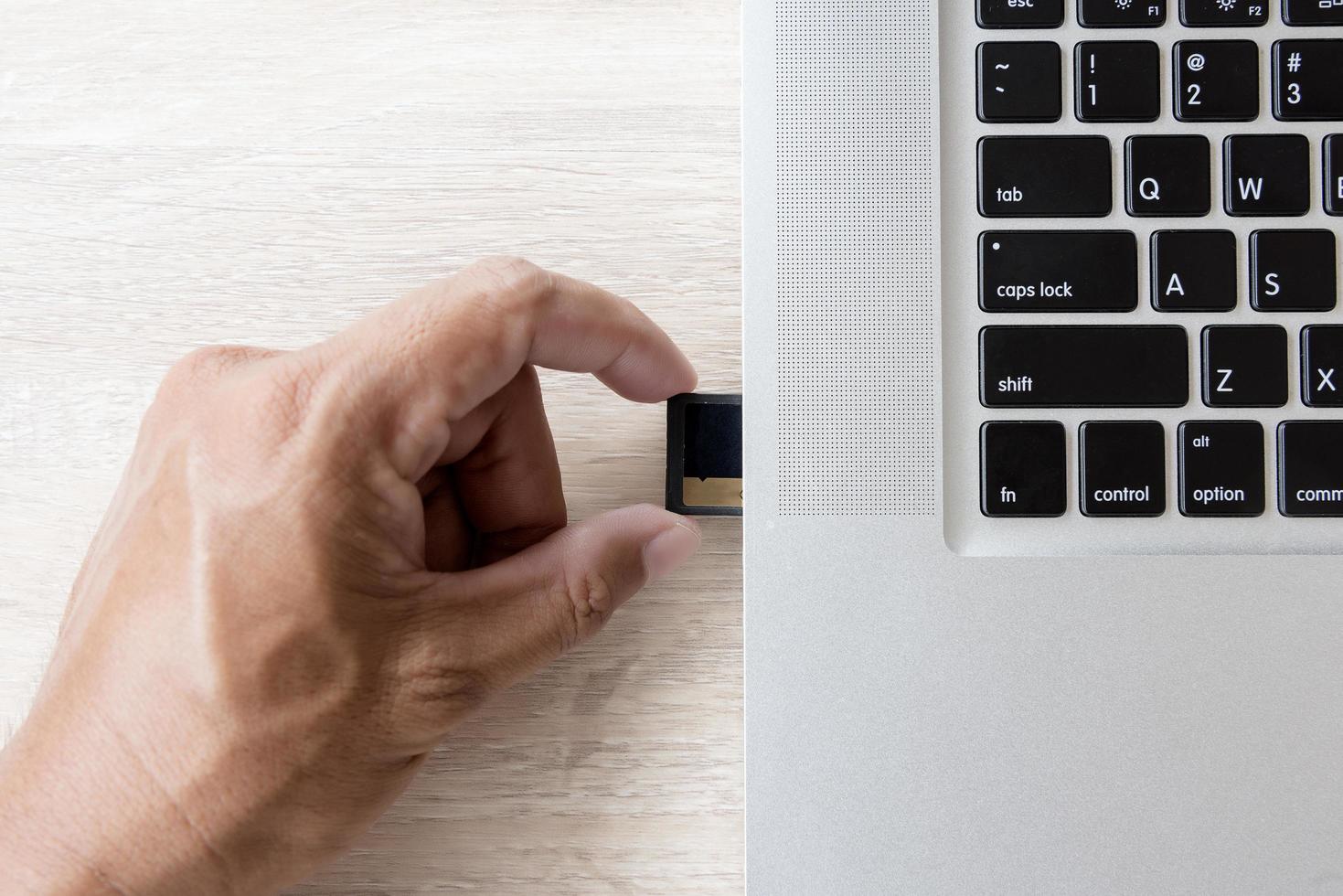 hand die een geheugenkaart in een laptopsleuf steekt foto