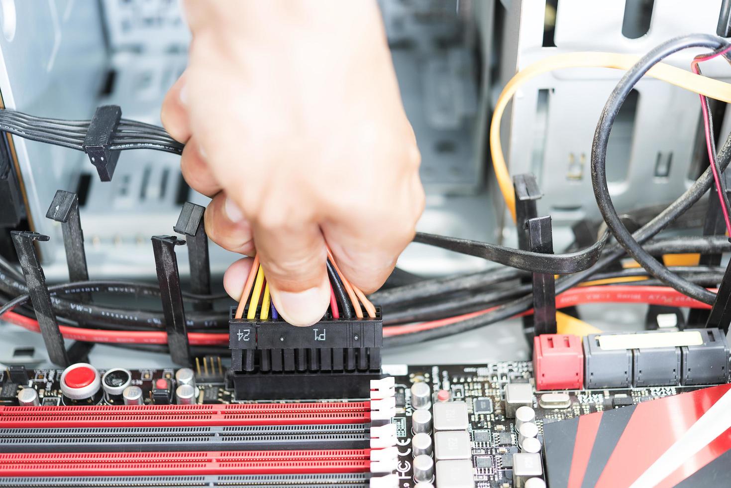 man's hand met een stekker en een kabel om verbinding te maken met een moederbordcomputer foto