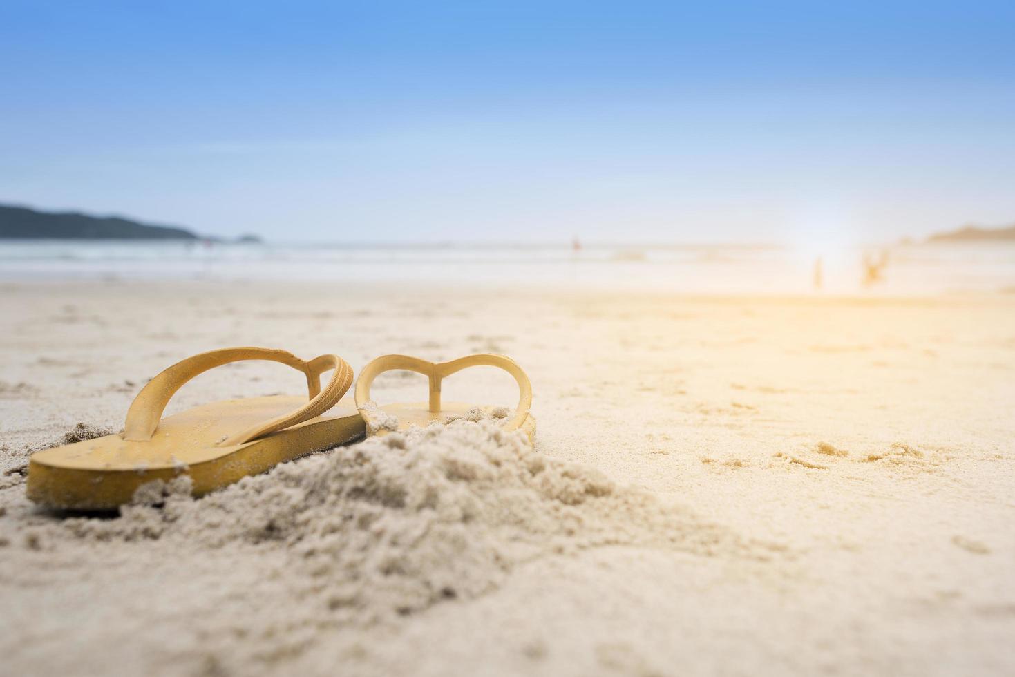 gele sandalen op het strand tijdens de zomer foto